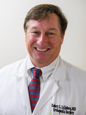 a man wearing a suit and tie smiling at the camera