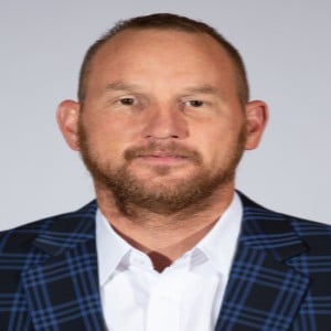 a man wearing a suit and tie smiling at the camera