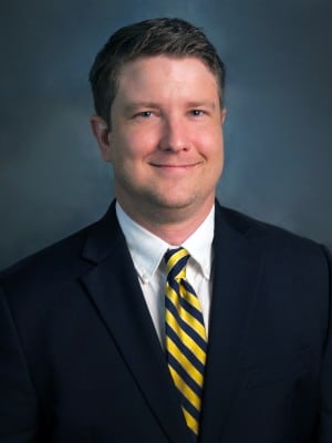 a man wearing a suit and tie smiling at the camera
