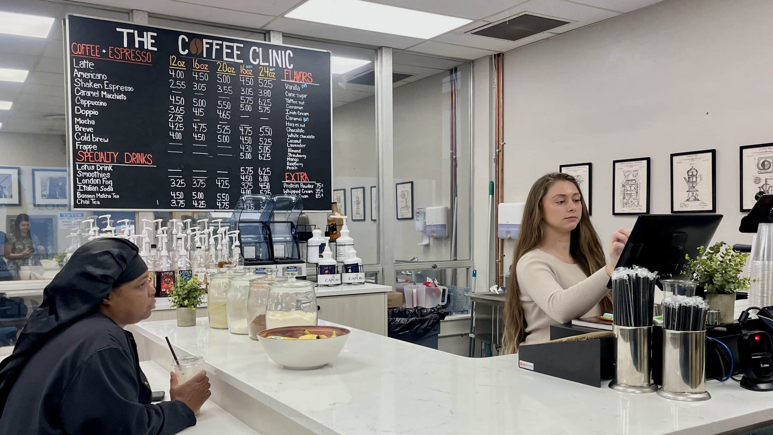 a group of people standing around a counter in a kitchen a group of people standing around a counter in a kitchen
