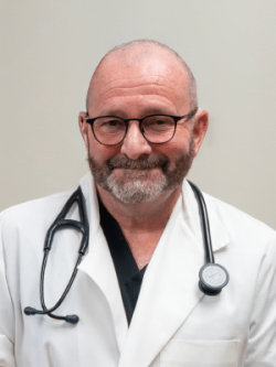 A Man Wearing Glasses And Smiling At The Camera