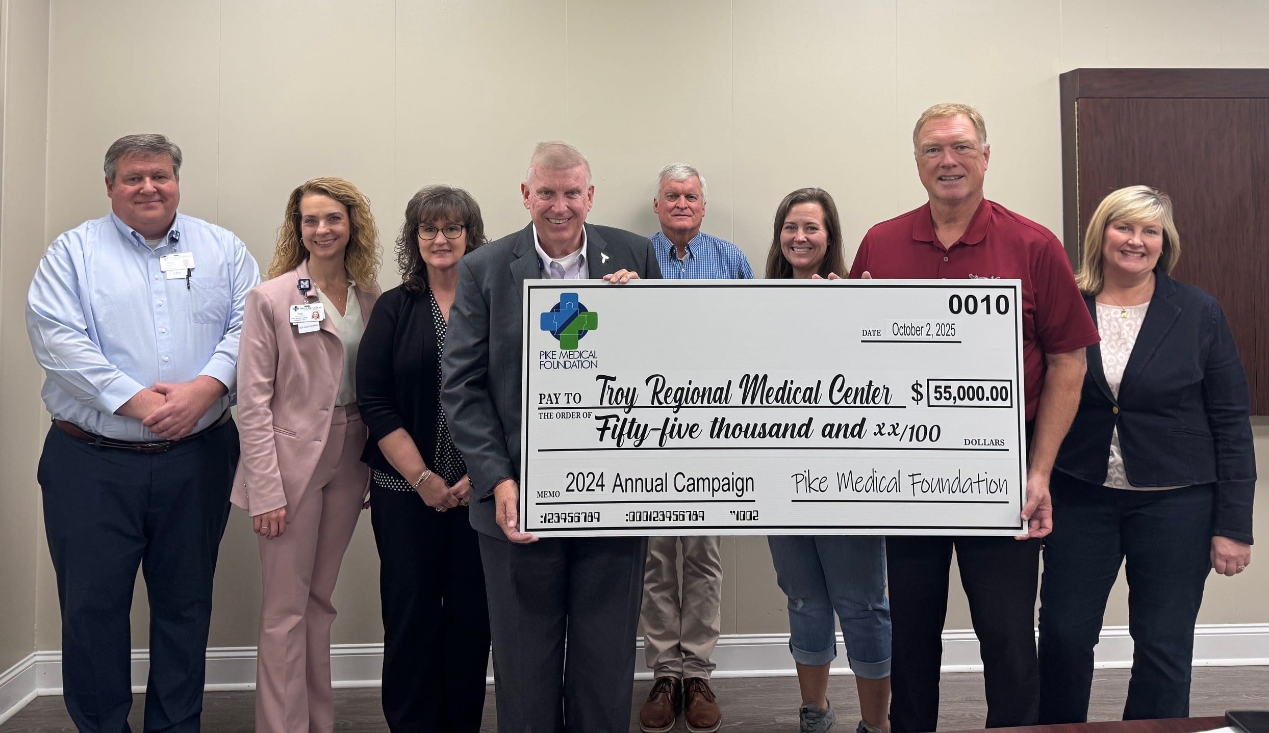 a group of people holding a donation check posing for the camera